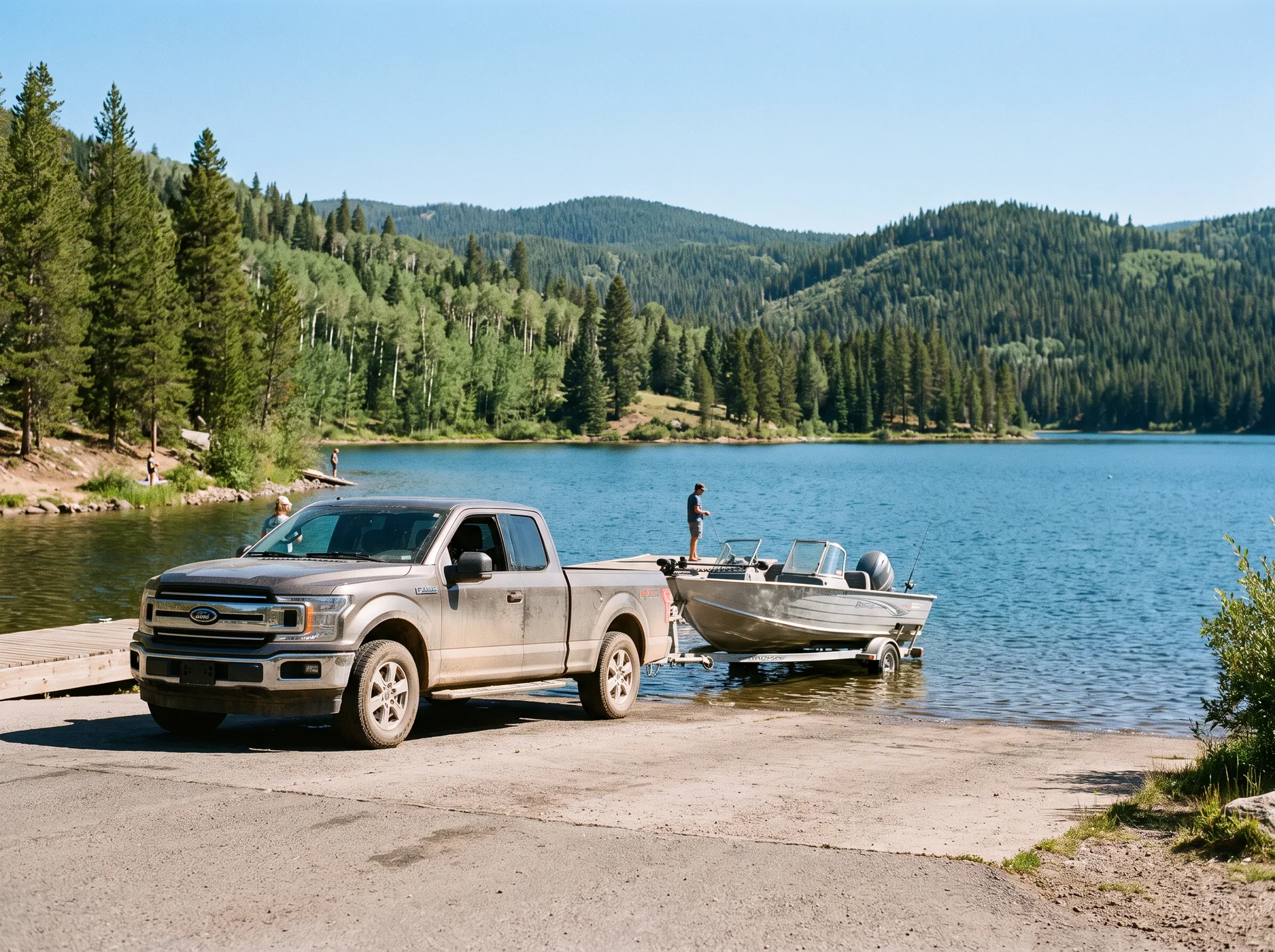 Truck backing a boat trailer down a launch ramp on a calm lake